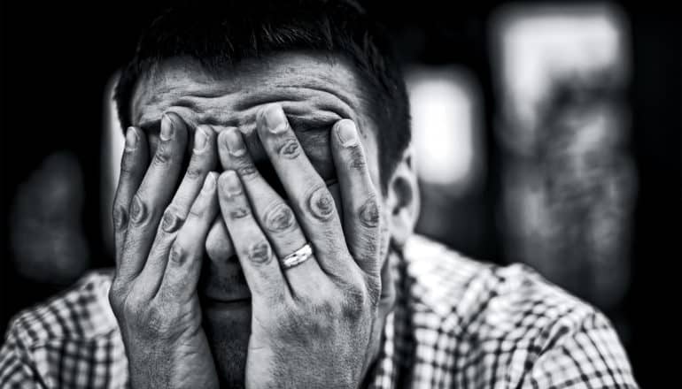 A young man puts his hands over his face in grief