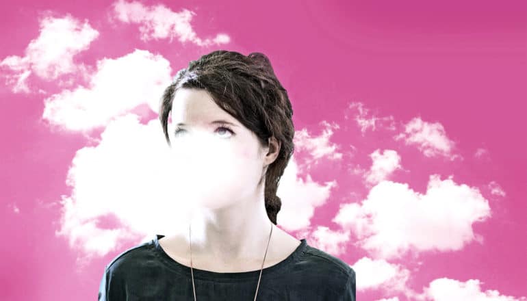 A young woman looks up as clouds surround her head against a pink background