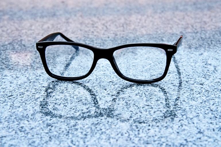 Black glasses sit on a marble-like reflective surface