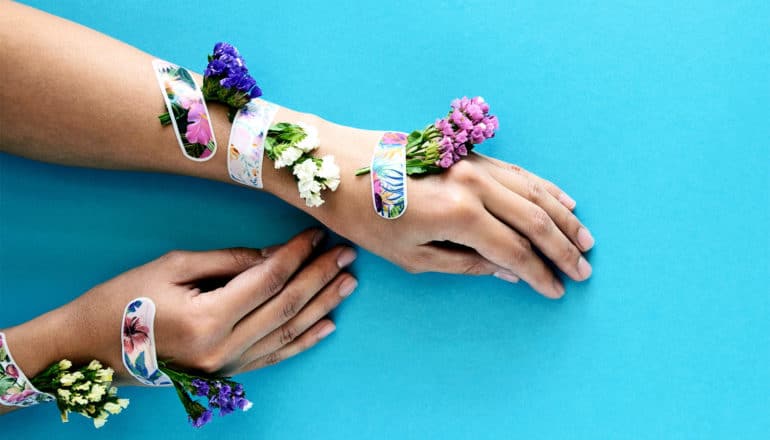 A person has their arms out with band-aids holding flowers to their arm