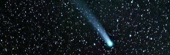 A comet streaks across a black, starry sky