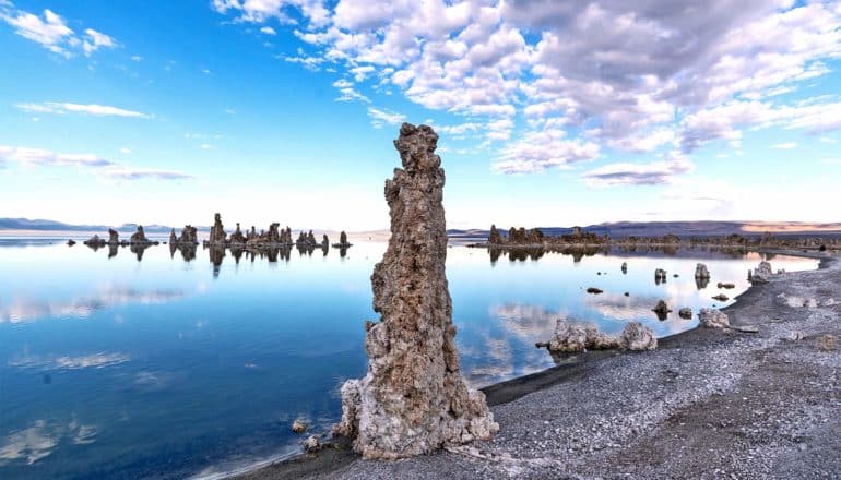 A bright blue lake reflects the blue, cloudy sky at