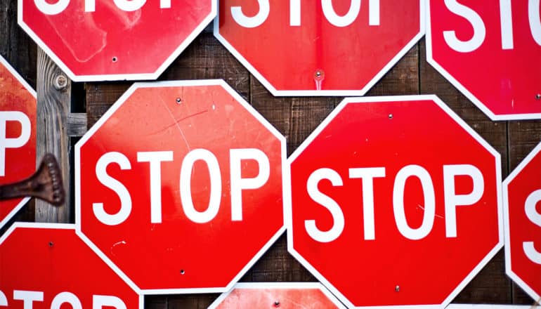 A series of stop signs cover a wooden wall