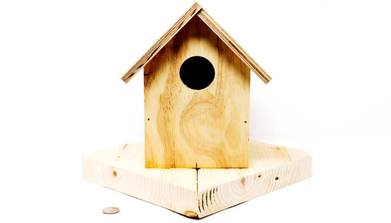 A wooden birdhouse sits on a white background