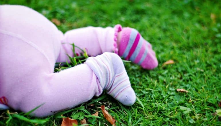 bottom and legs of crawling baby in grass