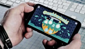 A person holds a phone showing the Gwakkamolé game, with the games title over a set of 4 avocado cartoon characters