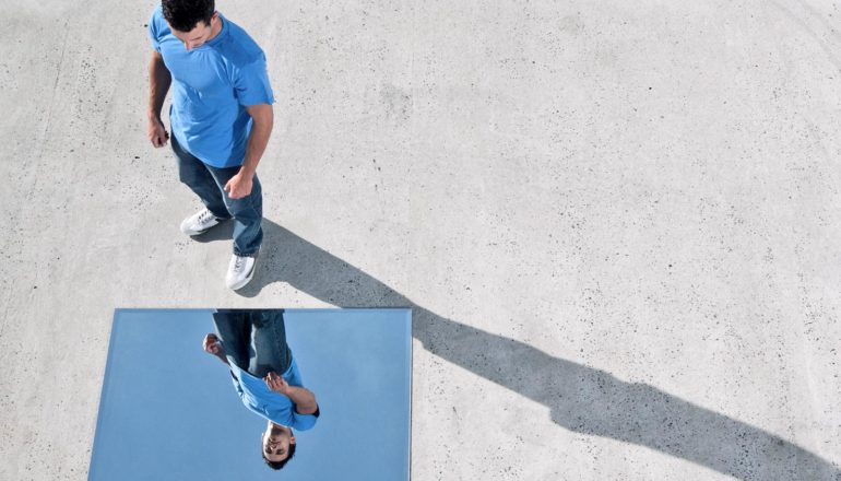 person looks at themself in mirror on the ground