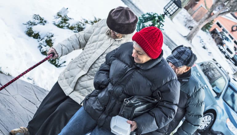 middle-aged person with elderly parents walk outdoors in winter