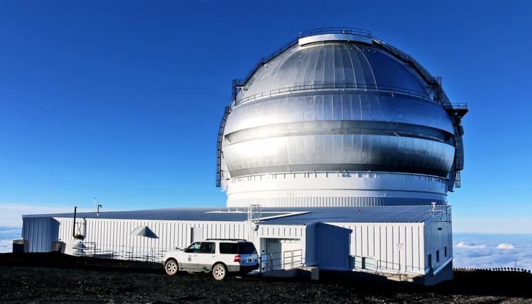 A large domed building sits on top of a mountain above the cloud line