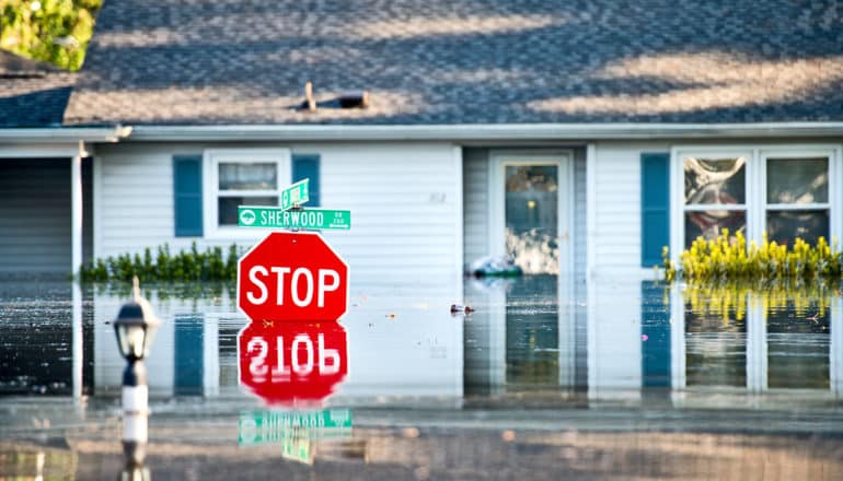 flood waters reach bottom of stop sign and street signs in front of home