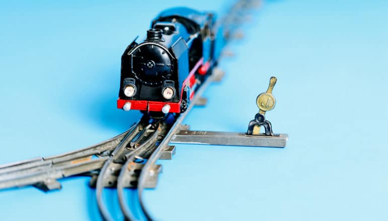 A toy train approaches a split in the track with a switch nearby