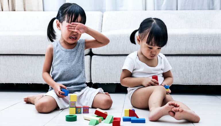 two little girls play with blocks; one cries (revenge concept)