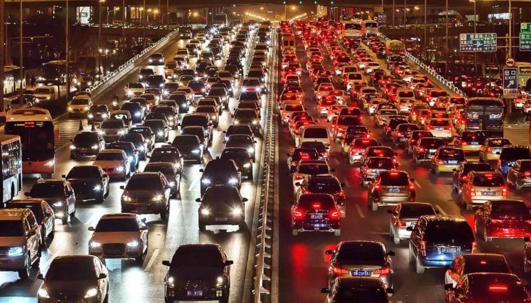 Standstill traffic in Beijing, with 4 or 5 lanes of cars coming towards the camera, and 6 lanes going away