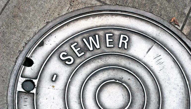A sewer cover on the street reads "sewer"