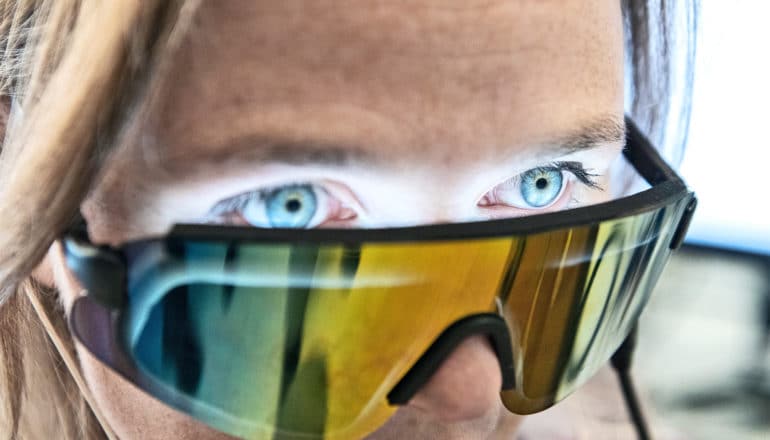 A researcher wears what look like large sunglasses, which shine light into her eyes