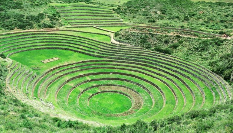 A grassy terrace descends into the earth, making a tiered, circular pit