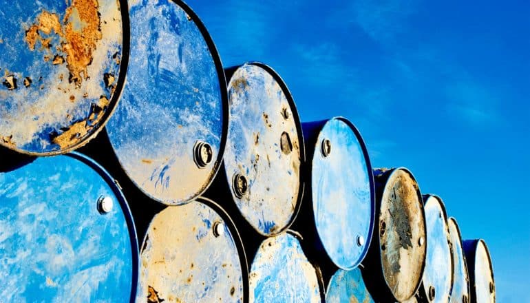 Rows of blue, rusting barrels sit against a blue sky