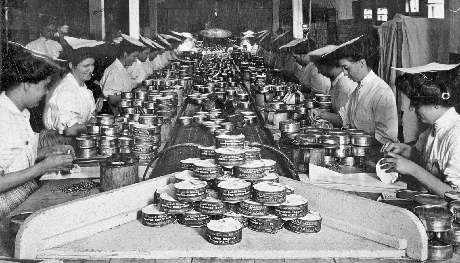 women at long table put labels on cans