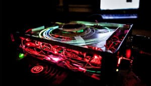 The concussion detection device sits on a table in a dark room, red lights coming from its open sides and green light coming from fibers coiled on its top