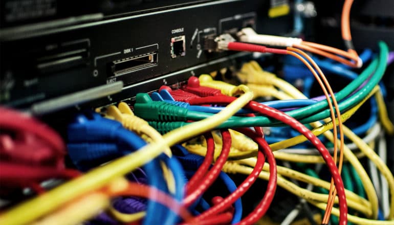 Multicolored data wires run into the plugs at a data center