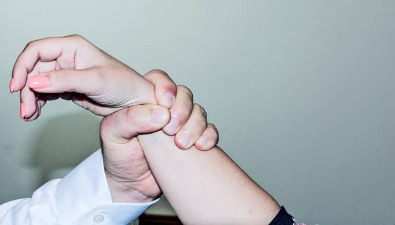 hand grips wrist of person with painted fingernails