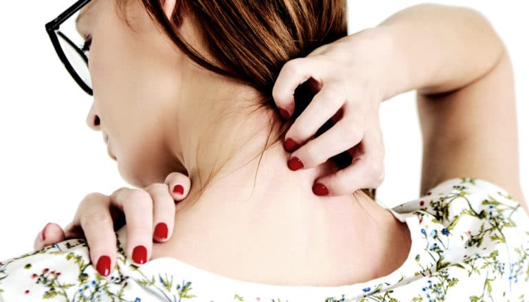 A young woman in a floral t-shirt scratches the back of her neck