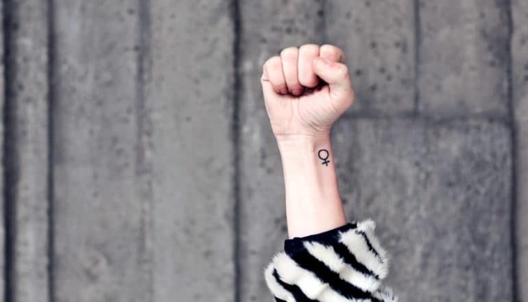 raised fist with woman symbol tattoo on wrist
