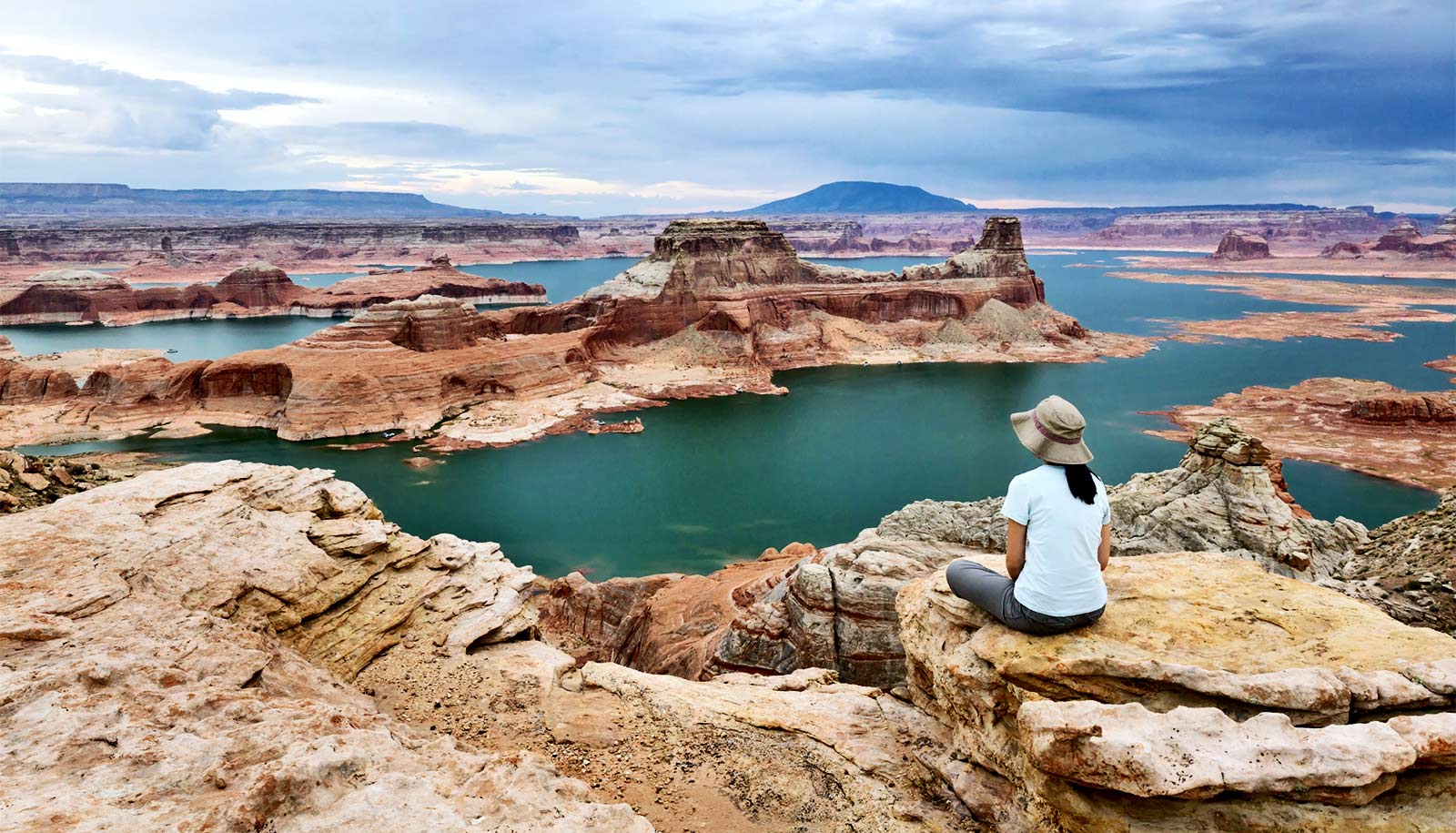 A woman looks out over Lake Powell, with patches of water broken up by red rock formations