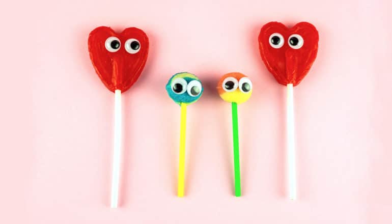 two larger heart-shaped lollipops with googly eyes with two smaller, round lollipops with googly eyes between them