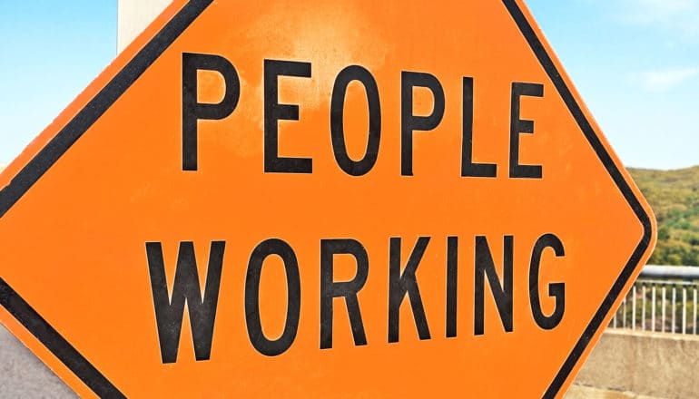 A road construction sign reads "People Working"