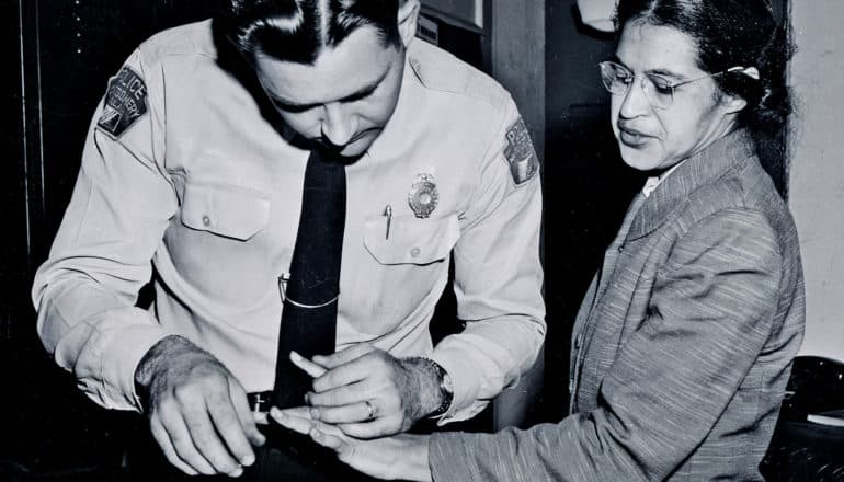 A uniformed police officer fingerprints Rosa Parks