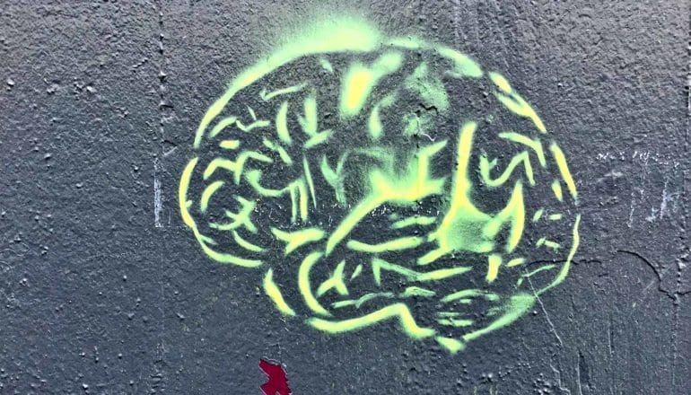 A brain is spraypainted on a dark grey wall
