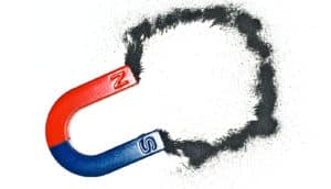 A magnet attracts iron filings, which are arranged in a circle on a while background