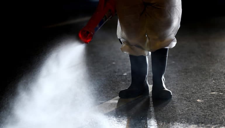 feet in boots and red tube spraying liquid