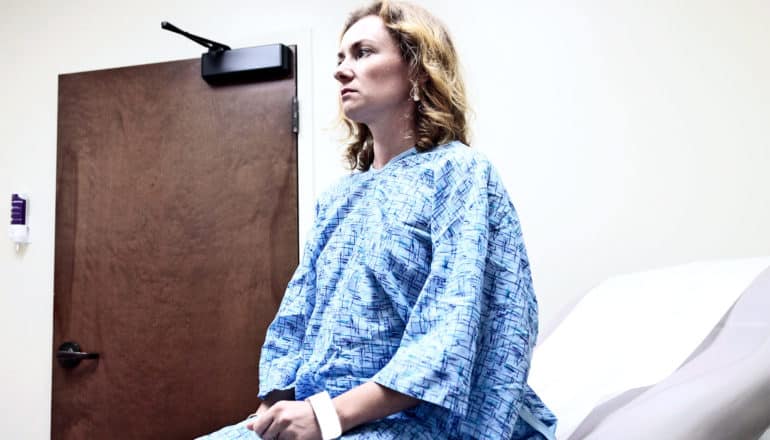 A woman sits on an exam table in a hospital doctor's office