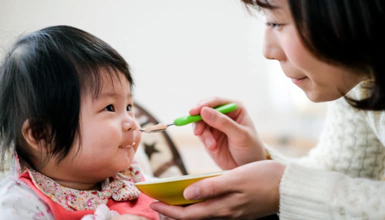 parent feeds baby with spoon