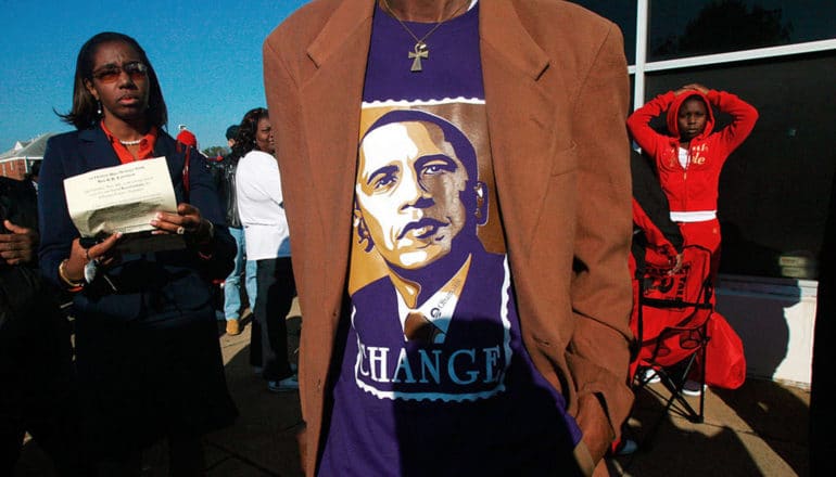 person in Obama t-shirt that says "change" under blazer. Person holding paper and child stand behind