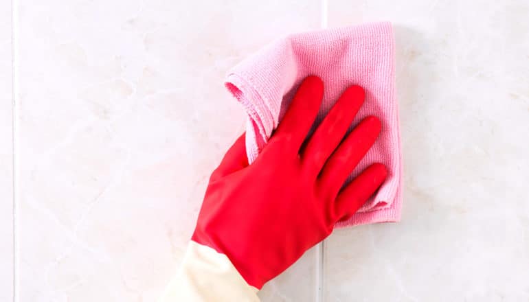 gloved hand holds cloth to tile
