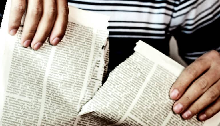 A man tears a newspaper in half