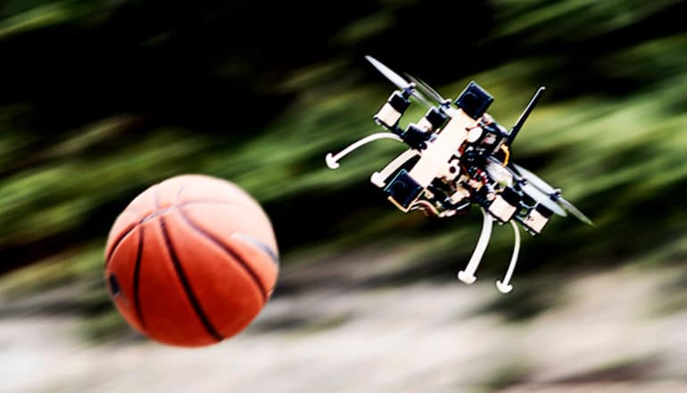 A quadcopter drone dodges a flying basketball