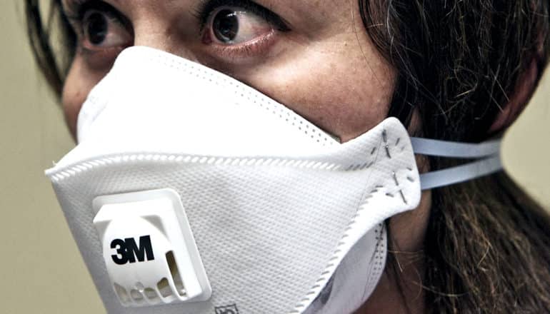 A woman wears an white n95 face mask with the 3M logo on it