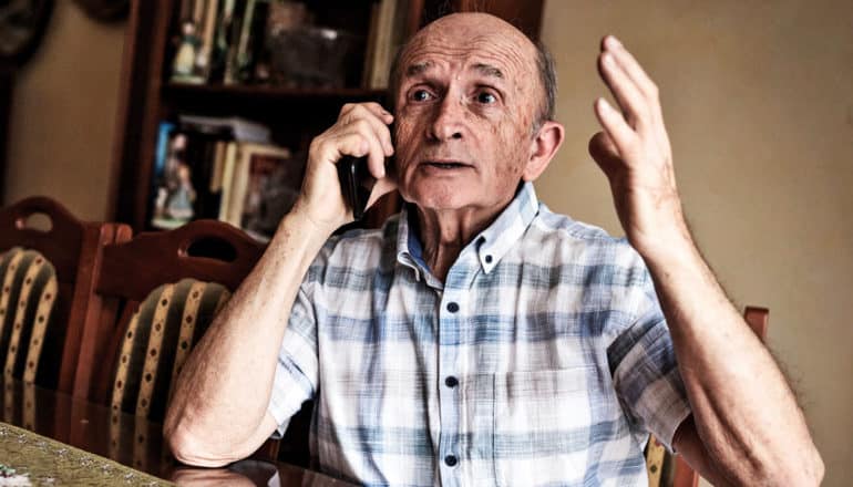 older person on phone looks exasperated with hand in the air