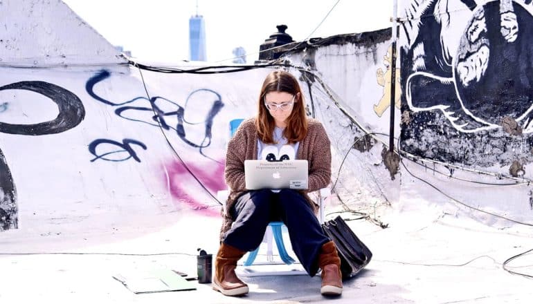 A teacher sits on her apartment rooftop with her laptop