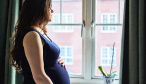 pregnant person looks out window