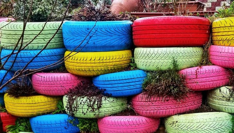A wall of colorful tires sit in a garden