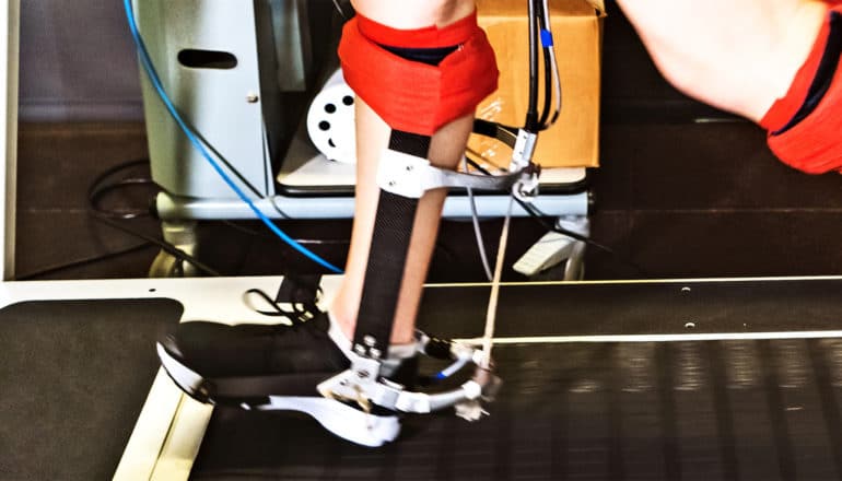 The exoskeleton is attached to a runner's leg as they run on a treadmill. The