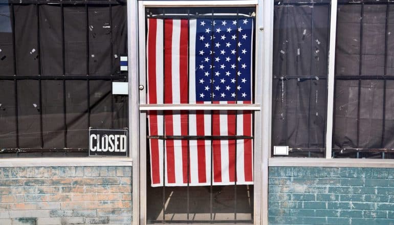 storefront with closed sign and US flag on door