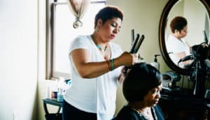 black woman styles customer's hair