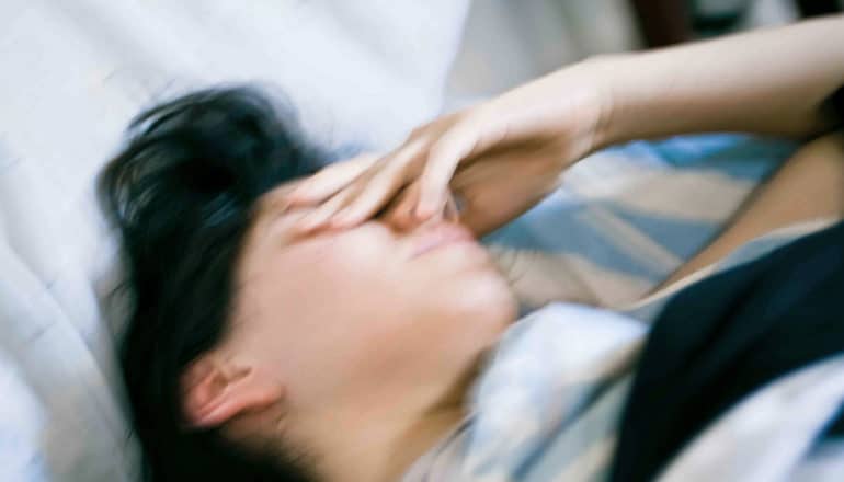 blurry photo of person in bed with hand on face