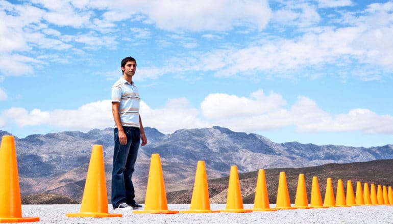 one person stands behind road cones in front of mountain vista